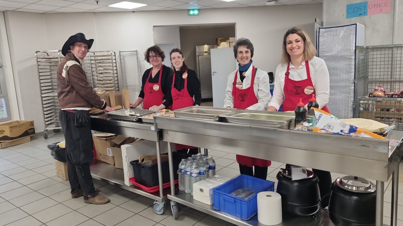 Équipe bénévole en tabliers rouges dans une cuisine d'événement