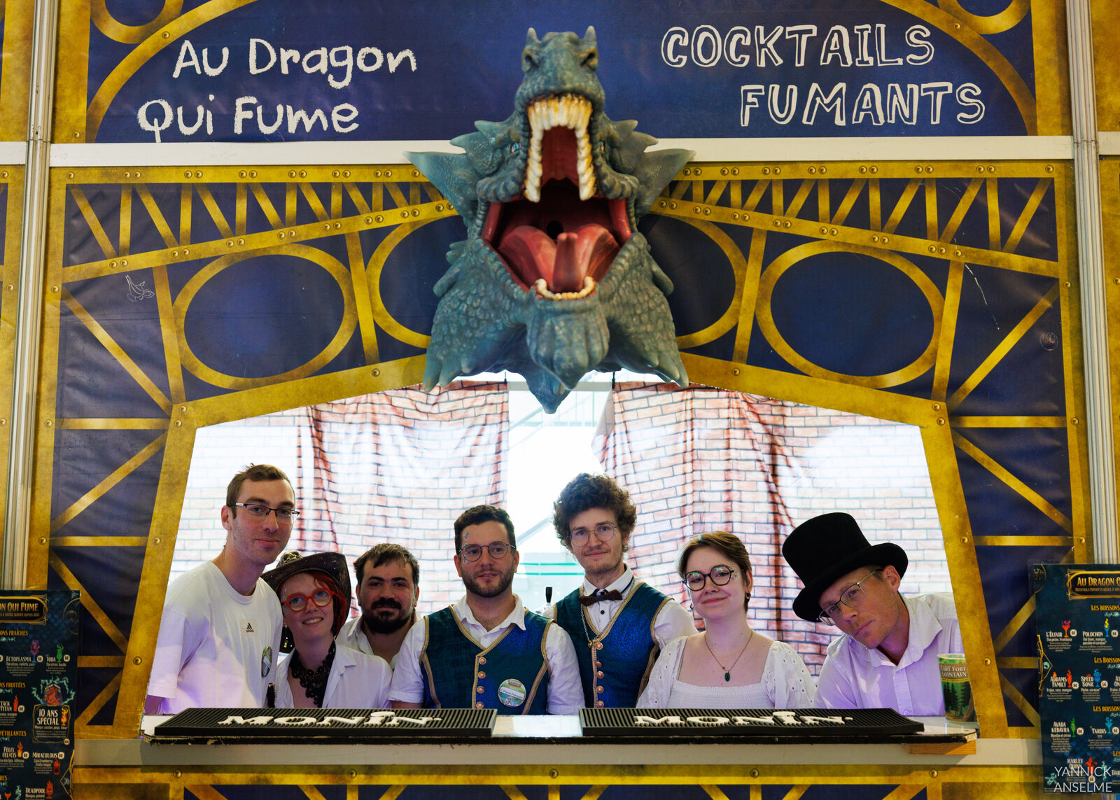 L'équipe du Dragon qui Fume derrière le bar fantasy, sous la tête de dragon