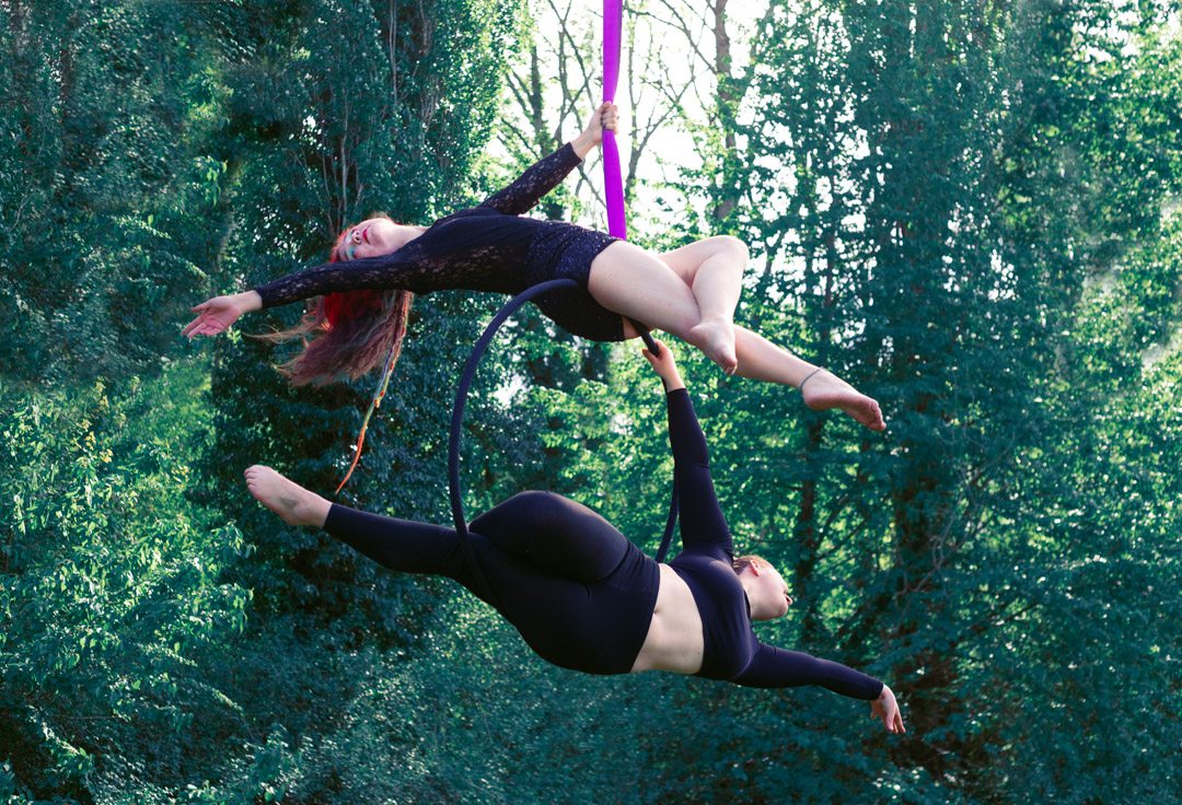 Duo d'artistes Yggdraïa en figure suspendue sur un même cerceau aérien, en pleine nature